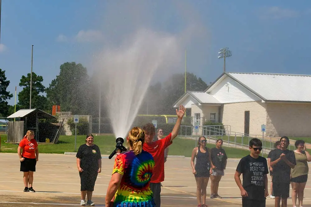 A little water from a firehose keeps the bad cool during marching practice.