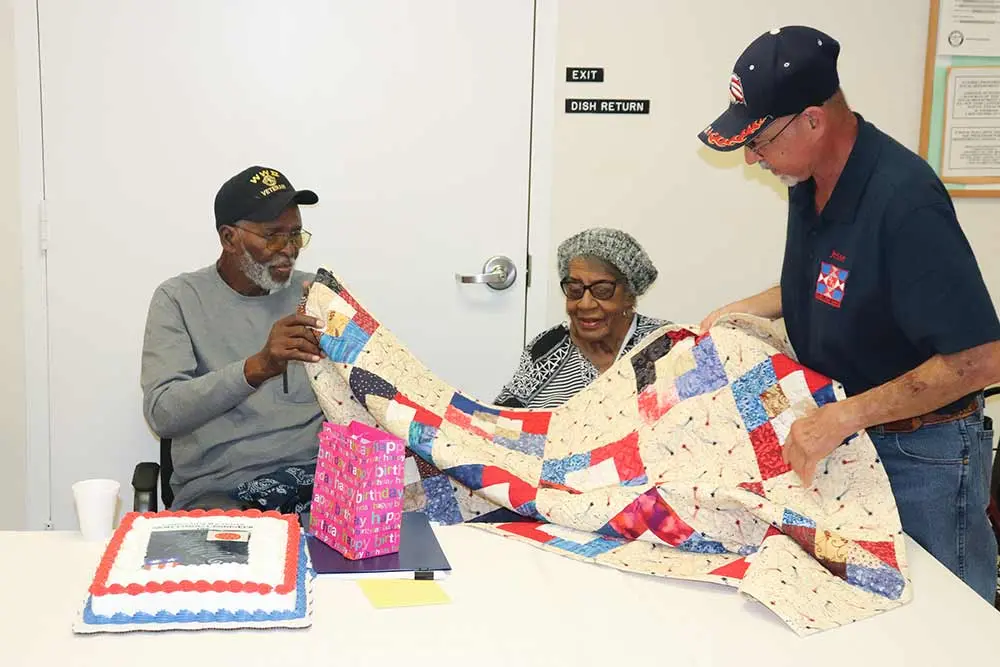 Jesse Gomez (right) gives a quilt to Alonzo Randolph. Gomez volunteers with Quilts for Vets, an organization that makes and gives quilts to veterans. Randolph’s wife Rosemary is also pictured. CHRIS EDWARDS | TCB 