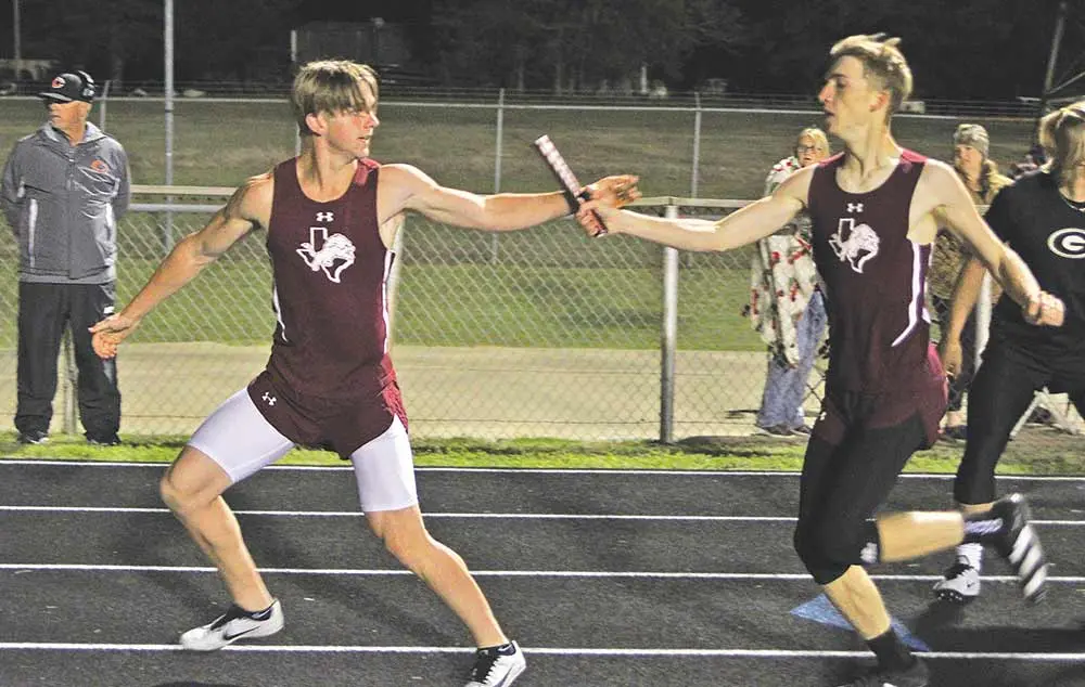 Lovelady's Seth Enos hands off to Alan Baskin in the 4x400 relay at the District 20-2A Track and Field Meet last Thursday night in Centerville. LARRY LAMB | HCC