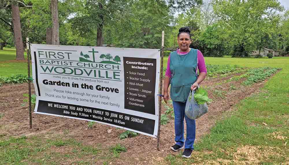 GARDEN IN THE GROVE  -  Sandra Hadnot is shown at the “Garden in the Grove,” located behind First Baptist Church of Woodville. The garden is a community outreach project by the church and several community volunteers aimed at providing produce for the community. There are several rows of good greens that are ripe for the pickin’. See story on page 3A.  Photo courtesy of Eleanor Holderman 