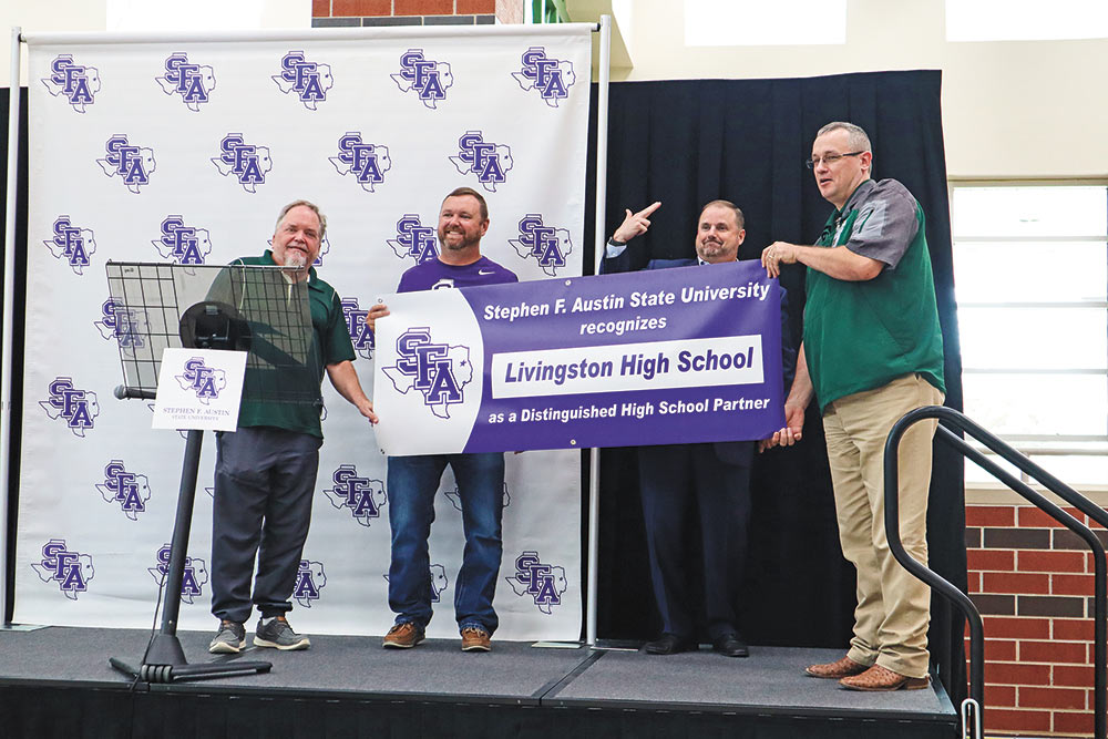 DISTINGUISHED HIGH SCHOOL PARTNER Unfurling a banner that states that Stephen F. Austin State University recognizes Livingston High School as a Distinguished High School Partner during a kick-off ceremony Friday are (l-r) LISD Board Member Kevin Wooten, Livingston High School Principal Dr. Paul Drake, SFA President Dr. Scott Gordon and LISD Superintendent Dr. Brent Hawkins. Photo by Emily Banks Wooten