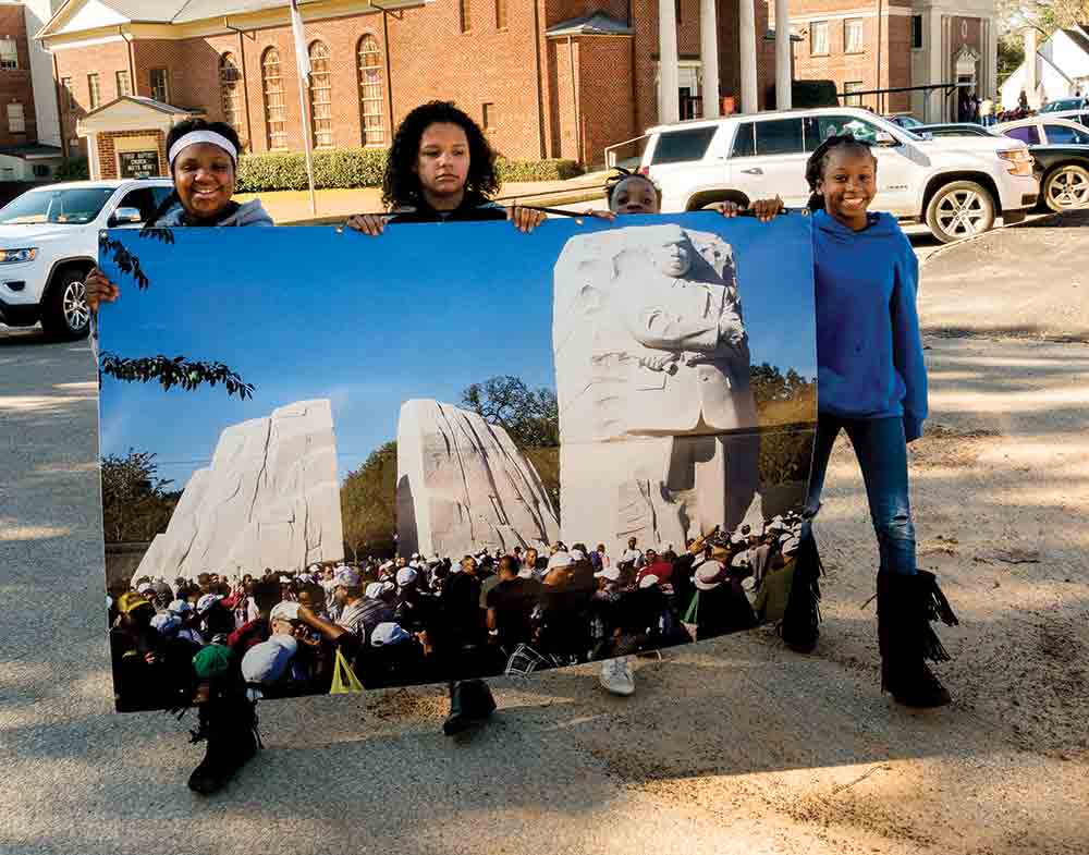 In this file photo from the citywide Woodville MLK Day celebration in 2018, a group of children hold up a print of a photograph taken at the Martin Luther King, Jr. Memorial in Washington, D.C. Jim Powers | TCB