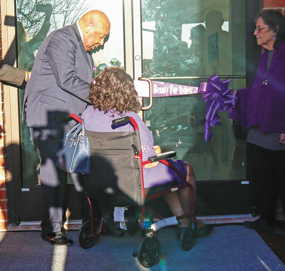 RIBBON CUT  Assisted by his wife, Clara, Col. Howard Daniel Jr., pastor of Chesswood Baptist Church, cuts the ribbon to the new church building following a dedication ceremony Thursday. The ceremony was held one year to the day that the church burned down.  Photo by Emily Banks Wooten